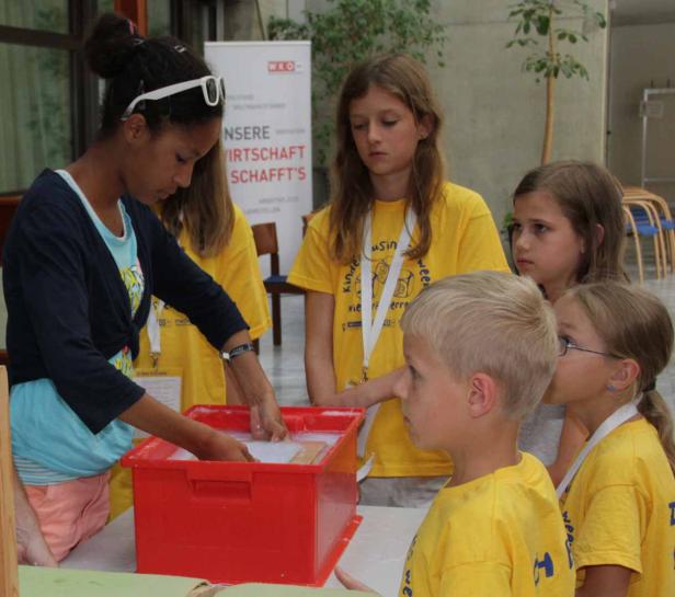 Eine junge Frau zeigt einer Gruppe von Kindern, wie man Papier schöpft.