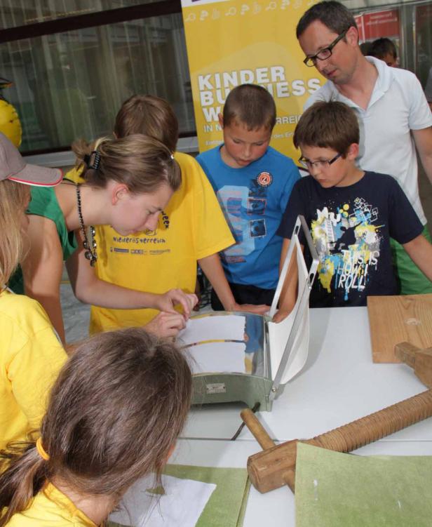 Kinder und ein Mann stehen um einen Tisch und arbeiten mit Holzwerkzeugen.