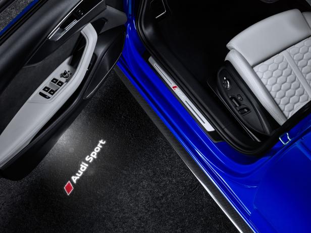 Der Innenraum eines blauen Audi RS4 mit beleuchtetem „Audi Sport“-Logo.