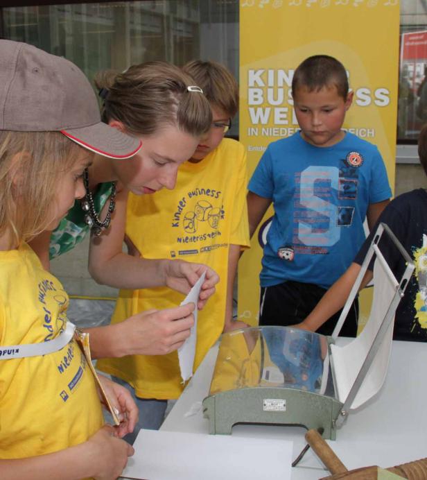 Eine Gruppe Kinder experimentiert mit einem Gerät im Rahmen einer „Kinder Business“-Veranstaltung.
