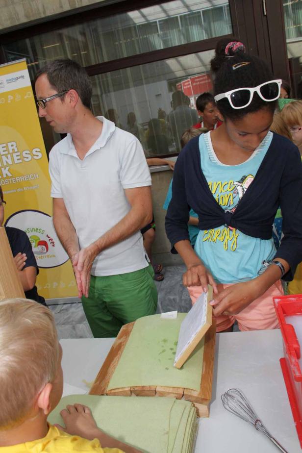 Ein Mädchen stellt mit Hilfe eines Mannes Papier her.