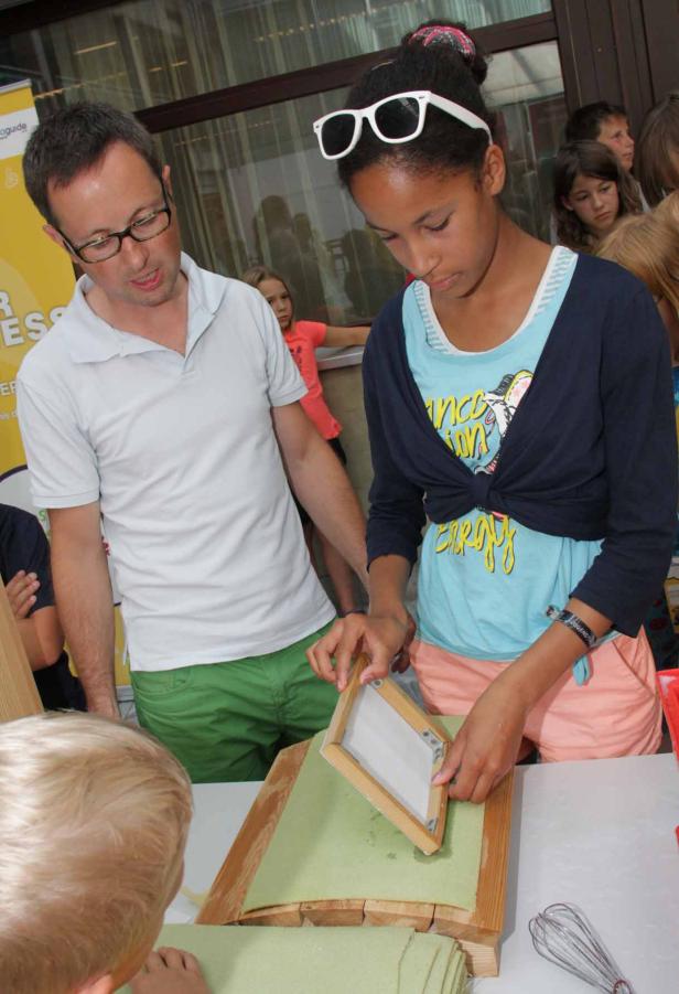 Ein Mädchen und ein Mann stellen Papier aus Zellstoff her.