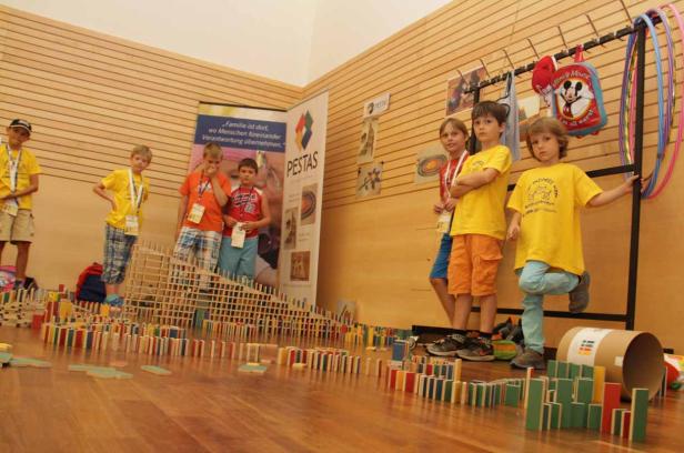 Eine Gruppe Kinder steht vor einer Konstruktion aus Dominosteinen.
