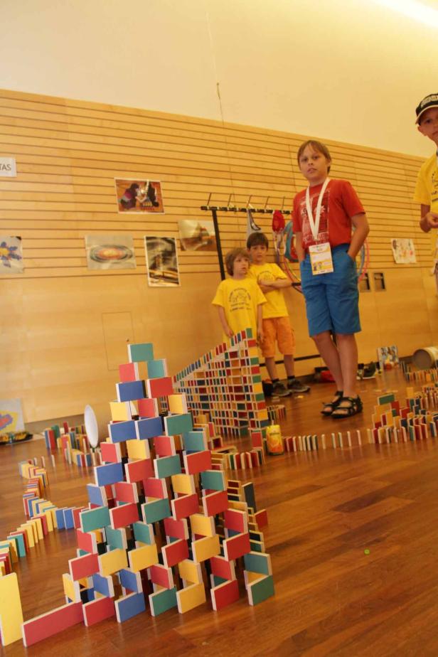 Kinder bauen mit bunten Dominosteinen eine Pyramide und eine lange Reihe.