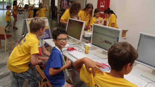 Eine Gruppe Kinder arbeitet an Computern in einem hellen Raum.