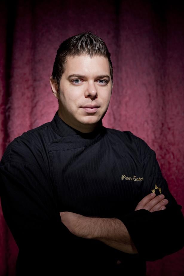 Ein Mann namens Peter Tinter in Kochuniform vor einem roten Hintergrund.