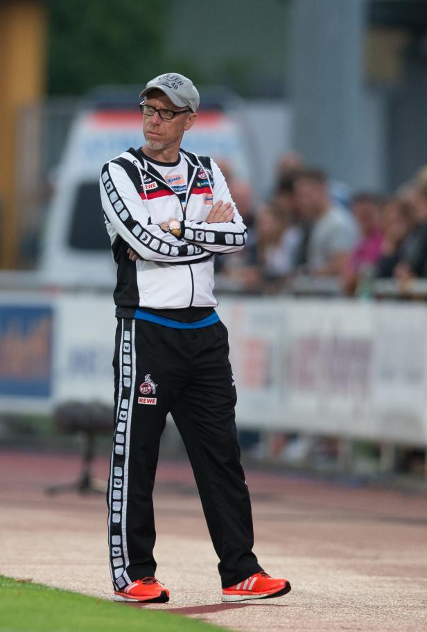 Ein Trainer des 1. FC Köln steht mit verschränkten Armen am Spielfeldrand.