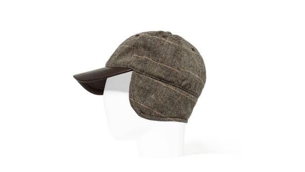 Eine braun-beige karierte Mütze mit Ohrenklappen und einem braunen Schirm auf einem weißen Hintergrund.