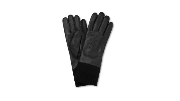 Ein Paar schwarze Lederhandschuhe mit Strickbündchen liegen auf einem weißen Hintergrund.