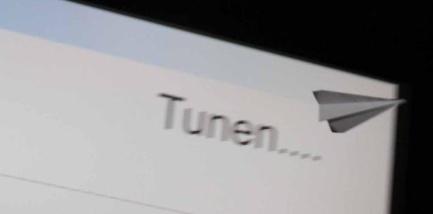Ein Papierflieger vor einem Bildschirm mit dem Wort „Tunen…“.