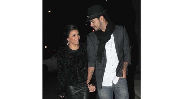 Eva Longoria Händchen haltend mit einem Mann in einem dunklen Anzug.