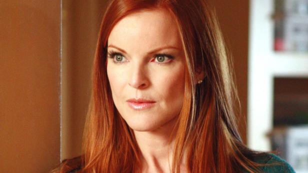 Eine Frau mit roten Haaren und hellen Augen schaut zur Seite.