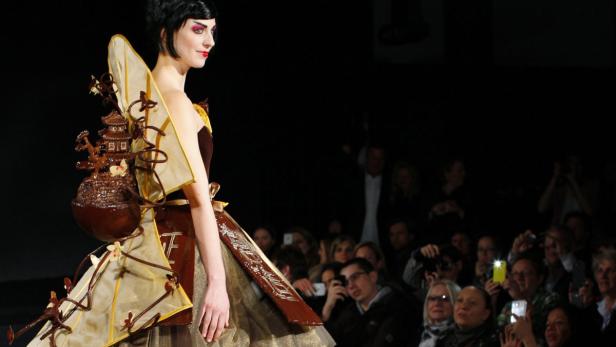 Eine Frau präsentiert ein aufwendiges Kleid aus Schokolade mit einer Miniatur-Pagode auf dem Rücken.