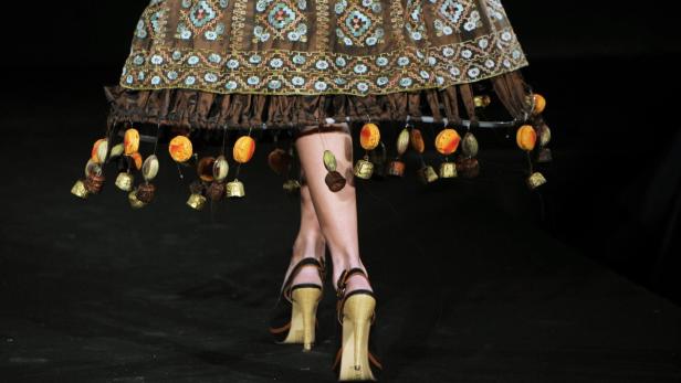 Nahaufnahme eines verzierten Rocks mit baumelnden Anhängern und dazu passenden High Heels.