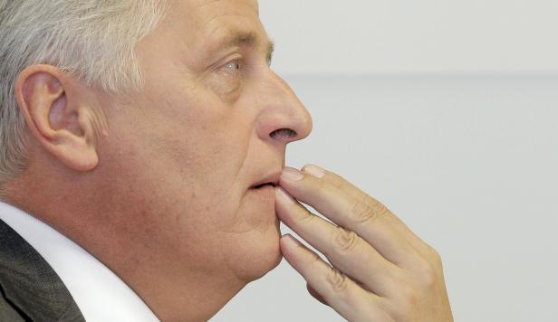 Ein Mann mit grauen Haaren berührt nachdenklich sein Kinn.