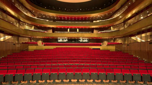 Blick auf die leeren roten Sitze und Ränge eines Theaters.
