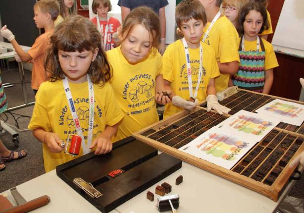 Kinder bedrucken Papier mit Stempeln während der Kinder Business Week.