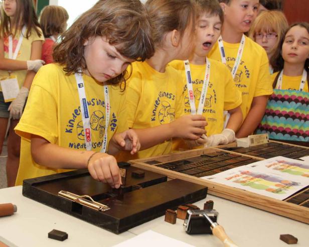 Kinder setzen Buchstaben in eine Druckform, um zu drucken.