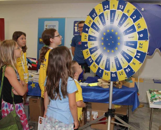 Kinder stehen an einem Stand mit einem Glücksrad zum Thema Europa.