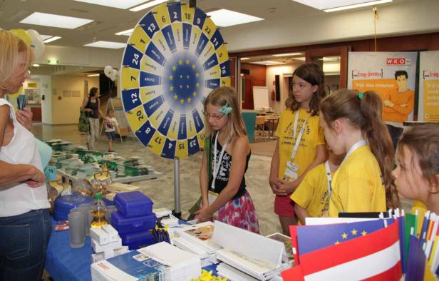 Kinder spielen an einem Stand mit einem Glücksrad zum Thema Europa.