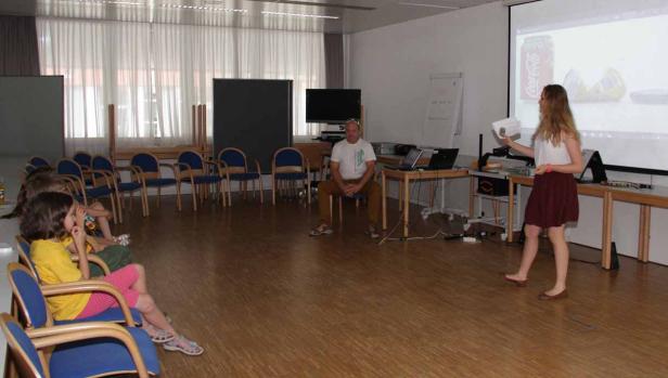 Eine junge Frau hält eine Präsentation vor einer kleinen Gruppe von Zuhörern.