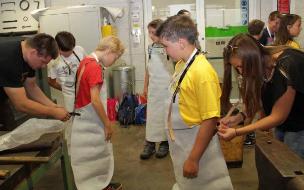 Schüler werden in einer Werkstatt mit Lederschürzen ausgestattet.