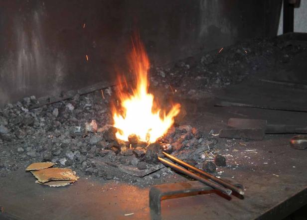 Ein Schmiedefeuer brennt hell in einer Esse.