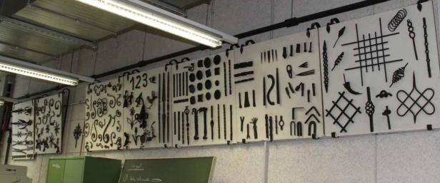Eine Wand mit einer Ausstellung von verschiedenen Schmiedeeisenarbeiten.