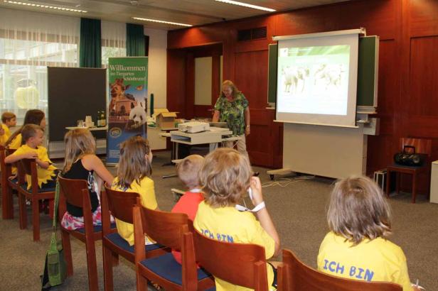 Kinder sitzen in einem Raum und schauen einer Präsentation über den Tiergarten Schönbrunn zu.