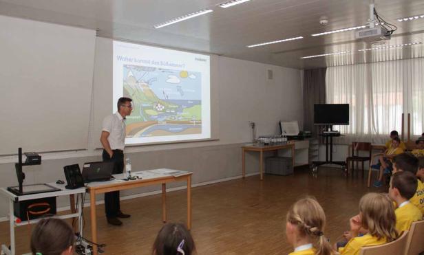 Ein Mann hält einen Vortrag über die Herkunft von Süßwasser vor einer Gruppe von Kindern.