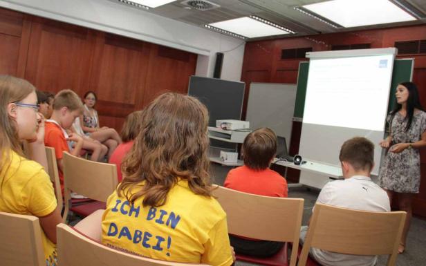 Eine Frau präsentiert vor einer Gruppe von Kindern in einem Klassenzimmer.