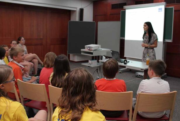 Eine Frau hält einen Vortrag vor einer Gruppe von Kindern.