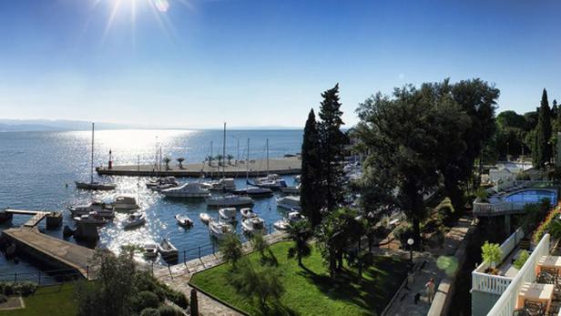 Blick auf einen Yachthafen mit zahlreichen Booten und einem Leuchtturm bei strahlendem Sonnenschein.