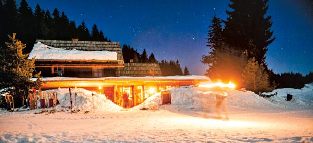 Eine Berghütte im Schnee unter einem sternklaren Nachthimmel.