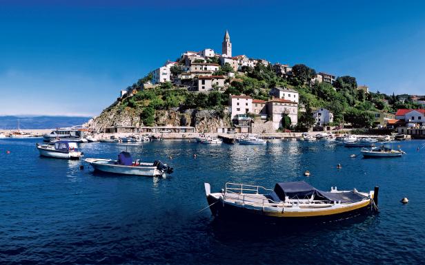Blick auf Vrbnik, eine Stadt auf der kroatischen Insel Krk, mit Booten im Wasser.