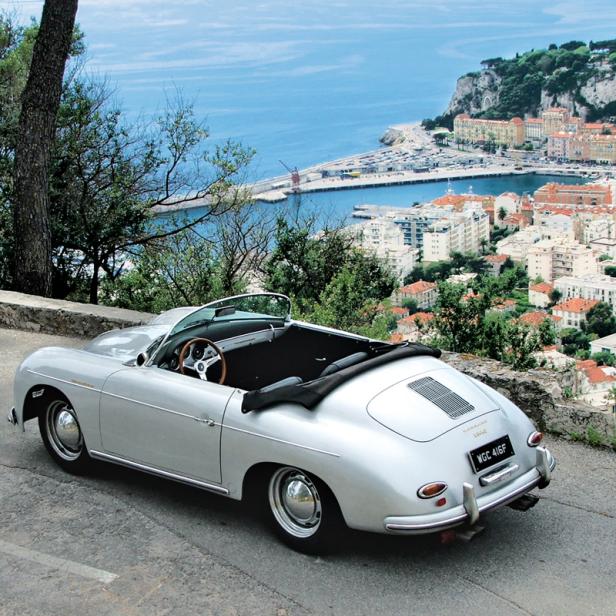 Ein silberner Porsche 356 Speedster mit Blick auf eine Küstenstadt.