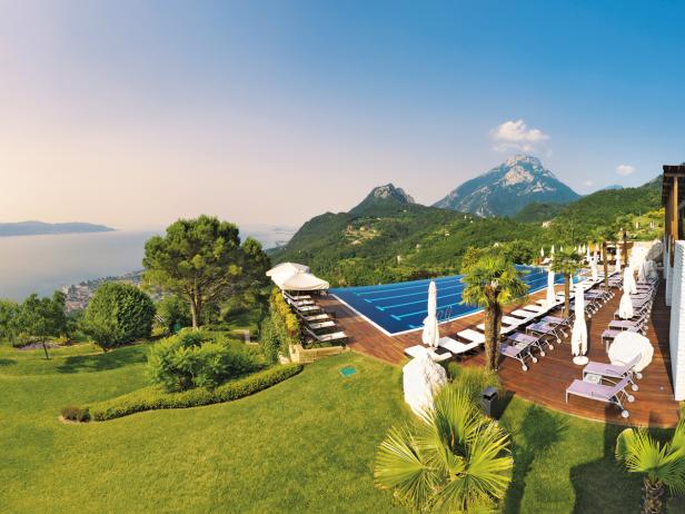Ein Schwimmbad mit Liegestühlen und Blick auf einen See und Berge.