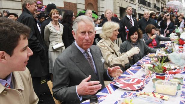 König Charles und Camilla nehmen an einer Straßenparty mit Union-Jack-Dekoration teil.