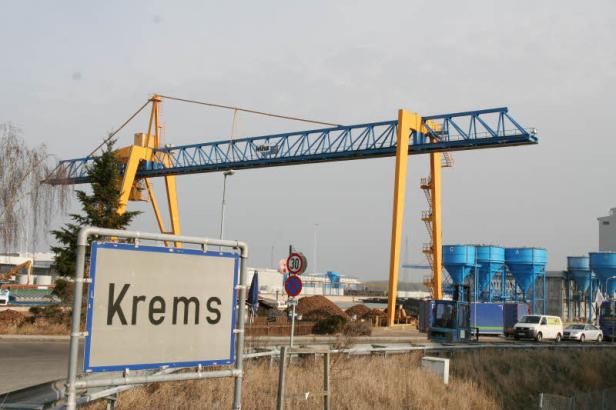 Ein blau-gelber Kran überblickt das Ortsschild von Krems an der Donau.