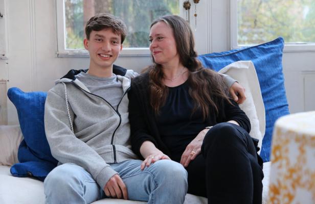 Ein junger Mann und eine Frau sitzen auf einem Sofa und lächeln.