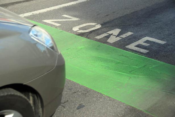 Ein Auto parkt neben einer grün markierten „Zone“ auf der Straße.