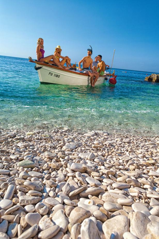 Eine Gruppe von Menschen genießt einen sonnigen Tag in einem Boot auf dem Meer.