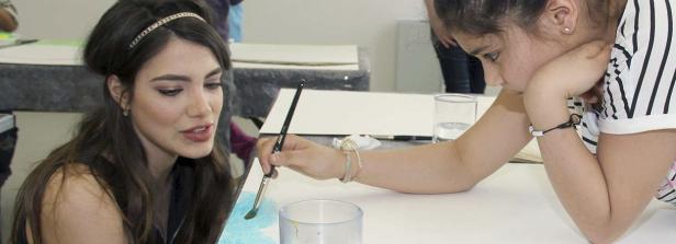 Eine Frau und ein Kind malen mit Pinseln auf Papier.