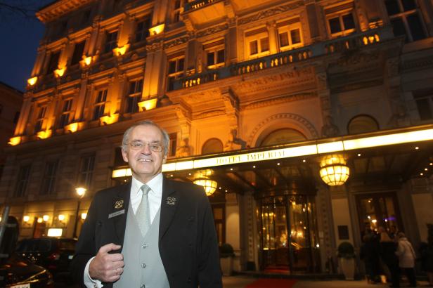 … Ein Portier steht vor dem beleuchteten Hotel Imperial in Wien.
