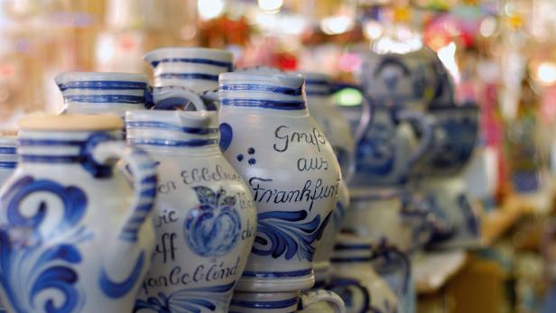 Mehrere Bembel, traditionelle Krüge, mit blauem Dekor und der Aufschrift „Gruß aus Frankfurt“.