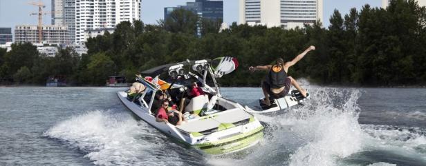 Ein Wakeboarder springt hinter einem Boot auf der Donau in Wien.