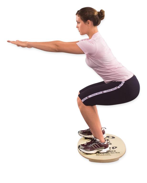 Eine Frau macht Kniebeugen auf einem Balance Board.