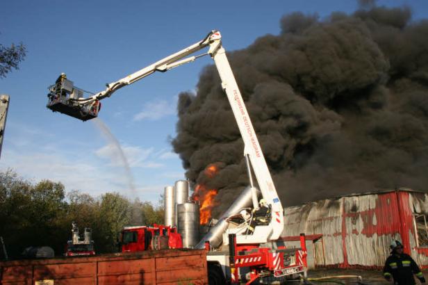 Feuerwehrleute bekämpfen einen Brand in einem Industriegebiet mit Drehleitern.