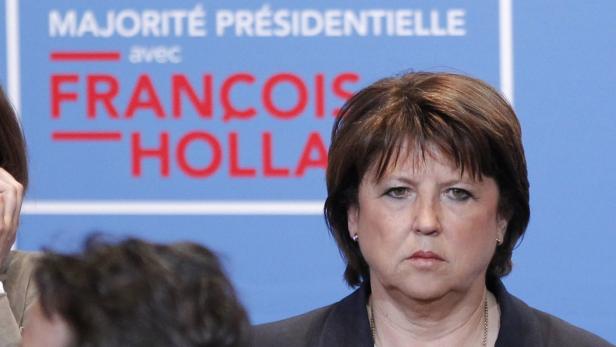 Eine Frau steht vor einem Wahlplakat für François Hollande.