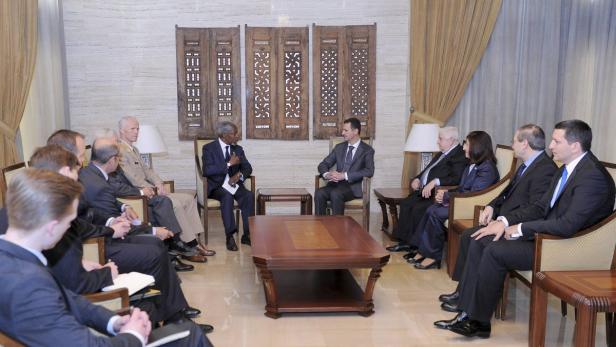 Kofi Annan und Baschar al-Assad sitzen sich in einem formellen Treffen gegenüber.